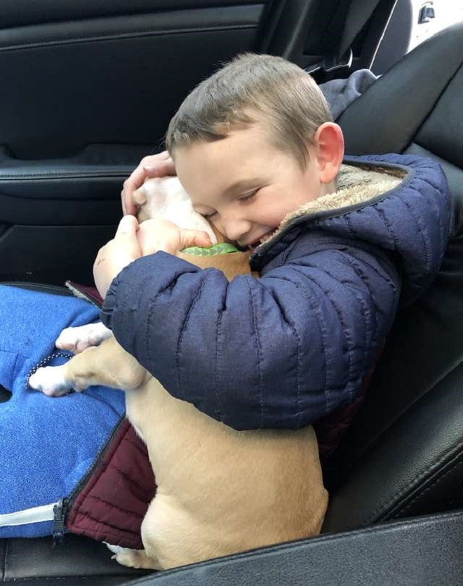 Мальчик обнимает щенка